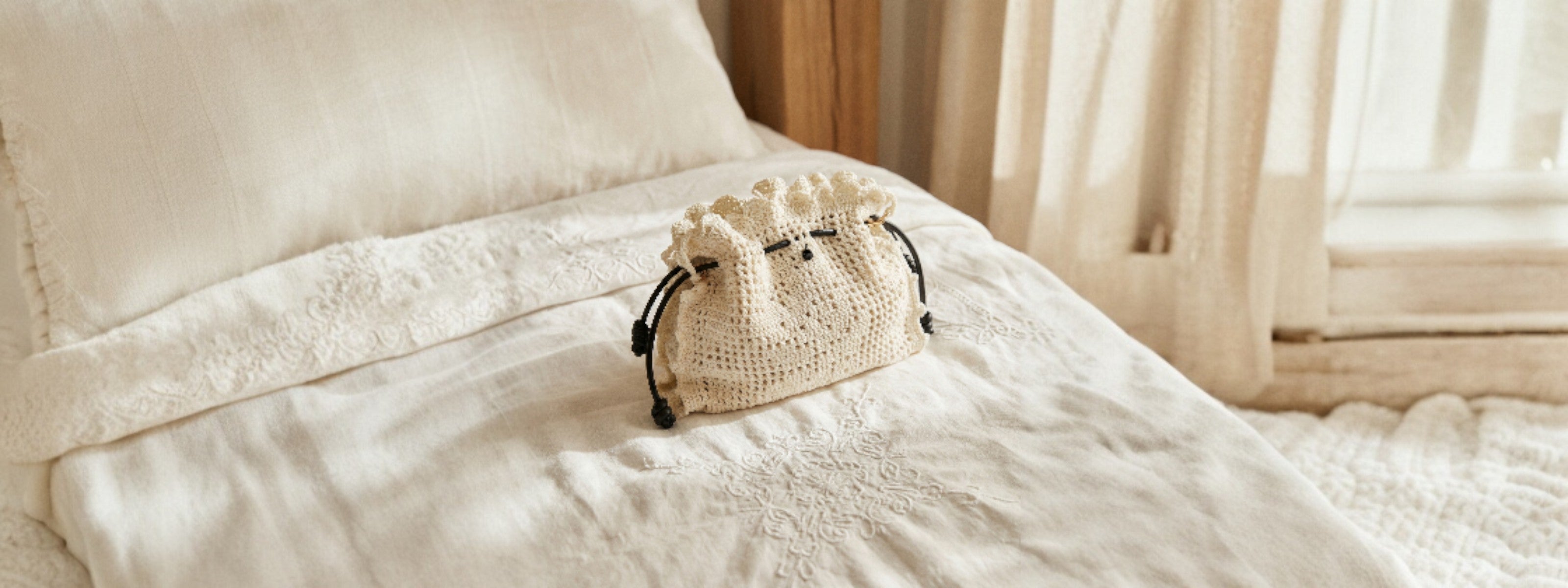 Bolso crochet artesanal Copenhague Lace en color crudo sobre sábana bordada blanca, colección SS2026 Ropa Blanca
