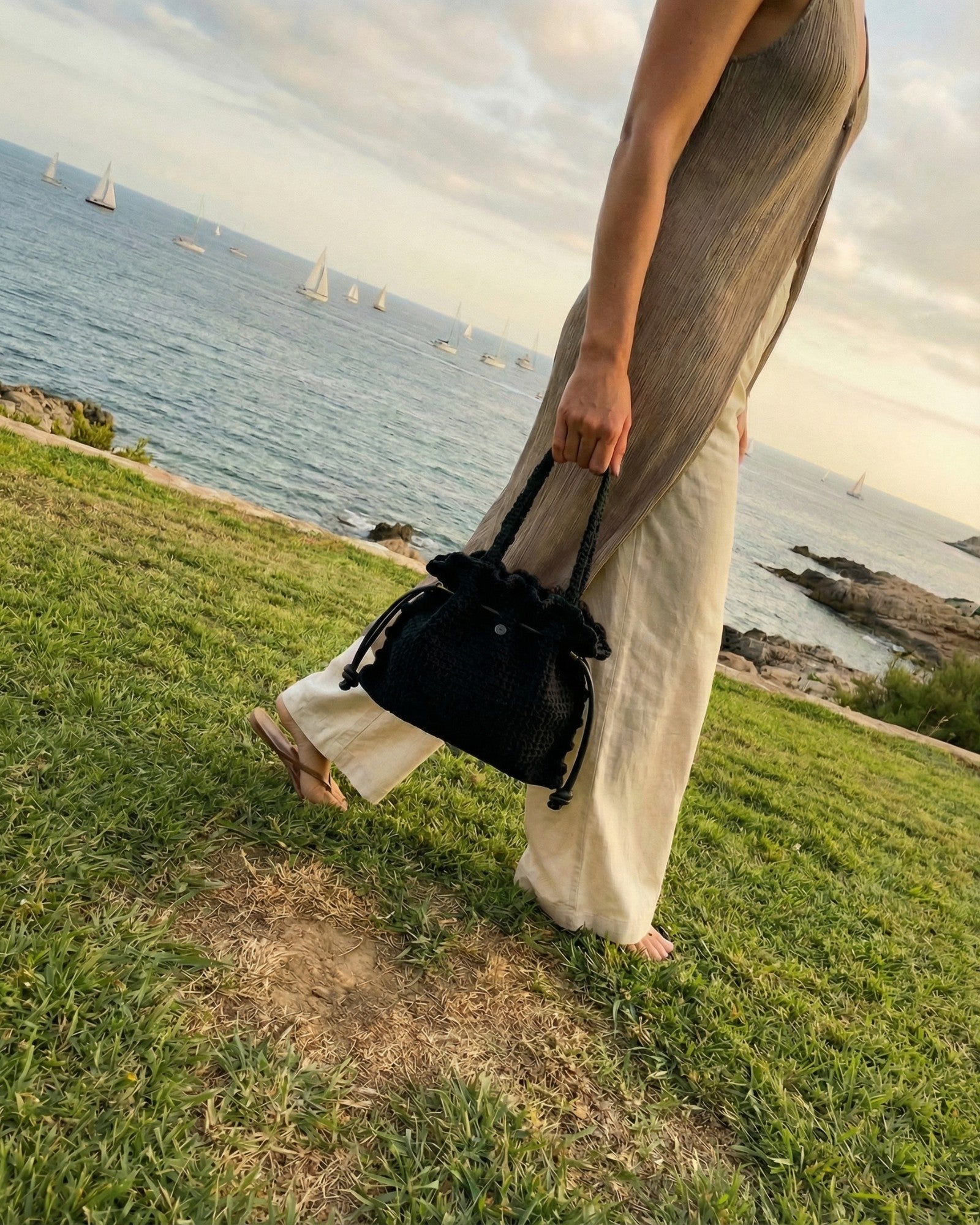 Bolso hecho a mano en negro con diseño textil inspirado en filet crochet sostenido por su asa de crochet