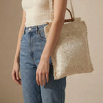 Tote Lace crudo colgado al hombro mostrando su tamaño.