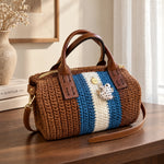 Bolso Bowling Urbana marrón de The Labbo, tejido a mano con franjas azul y crudo, sobre una consola de madera.