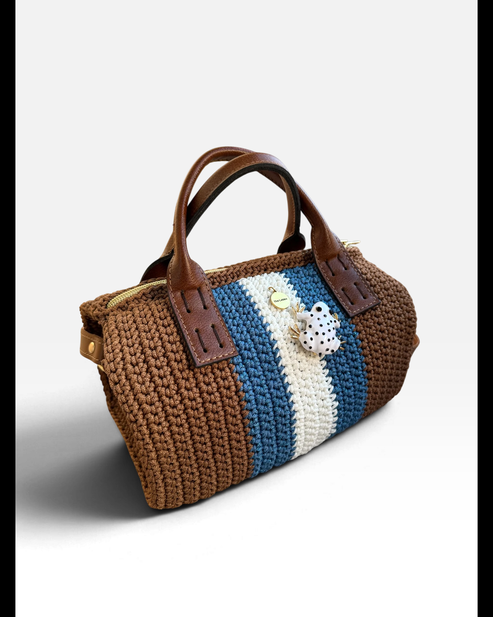 Vista lateral del bolso Bowling Urbana marrón con franjas azul y crudo y ranita esmaltada