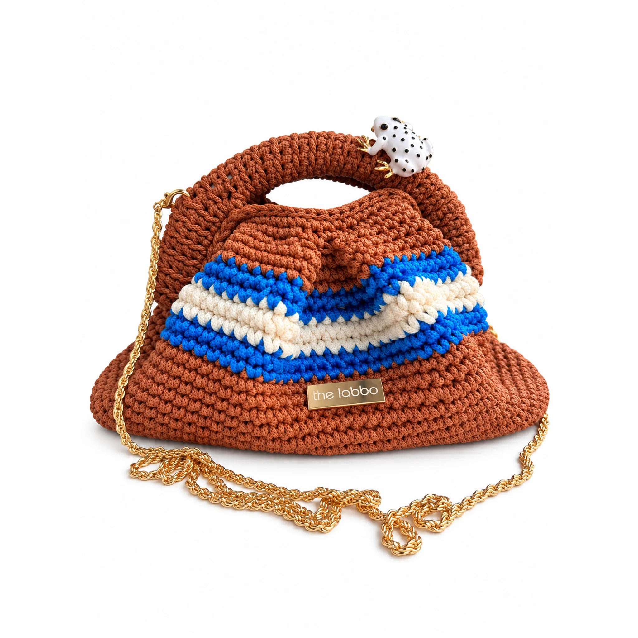 Clutch Urbana de The Labbo en terracota, azul y crudo con cadena de latón bañada en oro sobre fondo blanco.