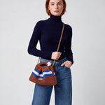 Modelo con jersey azul marino y vaqueros llevando el Clutch Urbana Terracota de The Labbo con su cadena dorada.