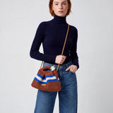 Modelo con jersey azul marino y vaqueros llevando el Clutch Urbana Terracota de The Labbo con su cadena dorada.