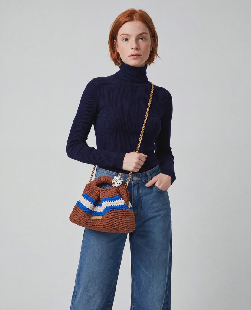 Fashion model turns slightly to the side while lifting the crocheted bag higher on her shoulder, camera pans gently left