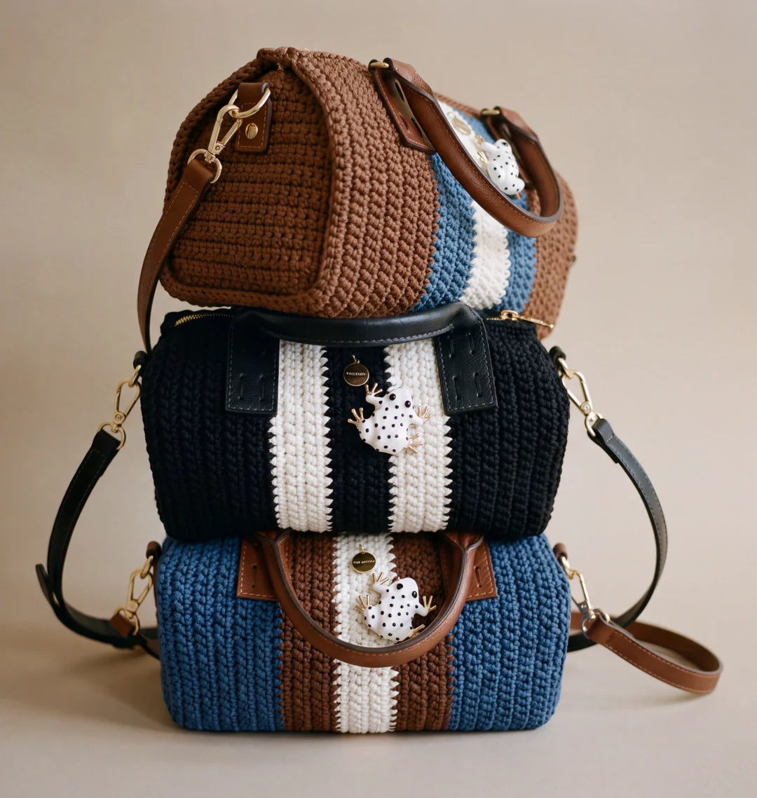 Tres bolsos Bowling Urbana de The Labbo en marrón, negro y azul denim, apilados sobre un fondo beige.